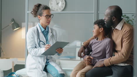 Female-Pediatrician-Giving-Consultation-to-African-American-Boy-and-His-Dad